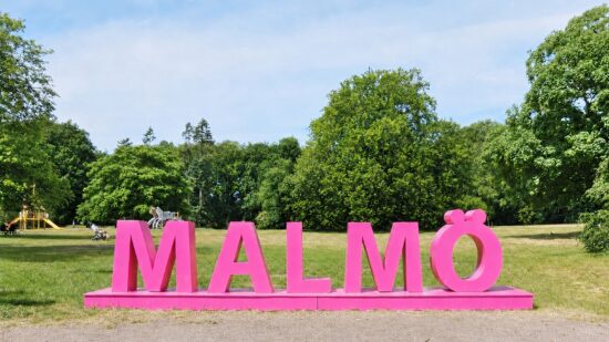 Malmöskylt i grön park som symboliserar Malmös olika bostadsområden